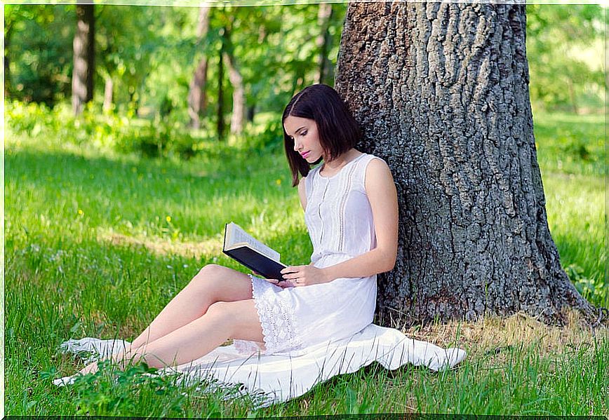 Woman reading a book under a tree