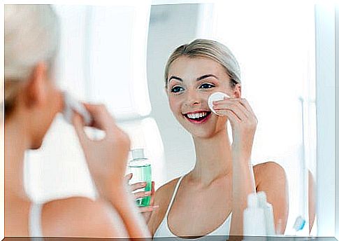 Woman applying a product to her face with a cotton pad.