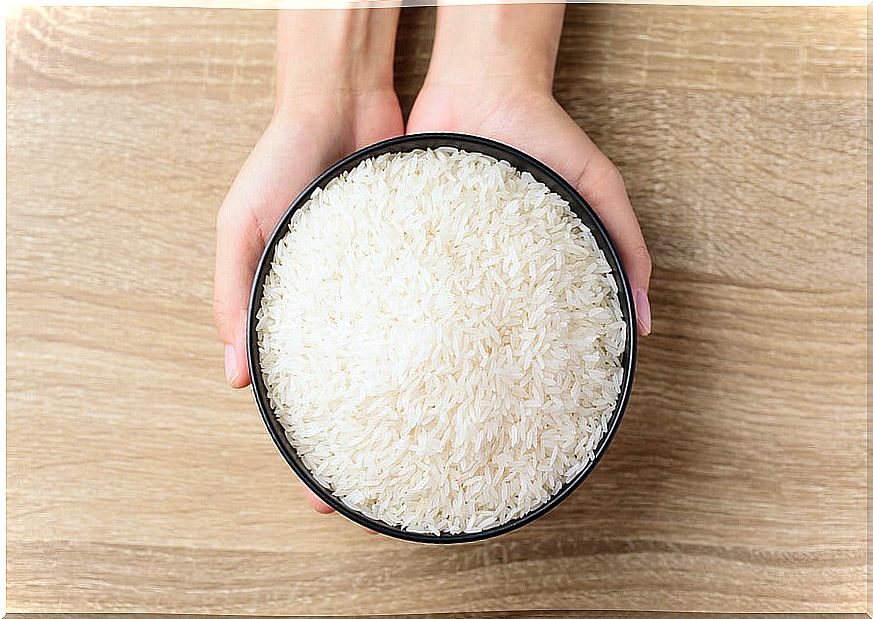 Hands holding a bowl of white rice.