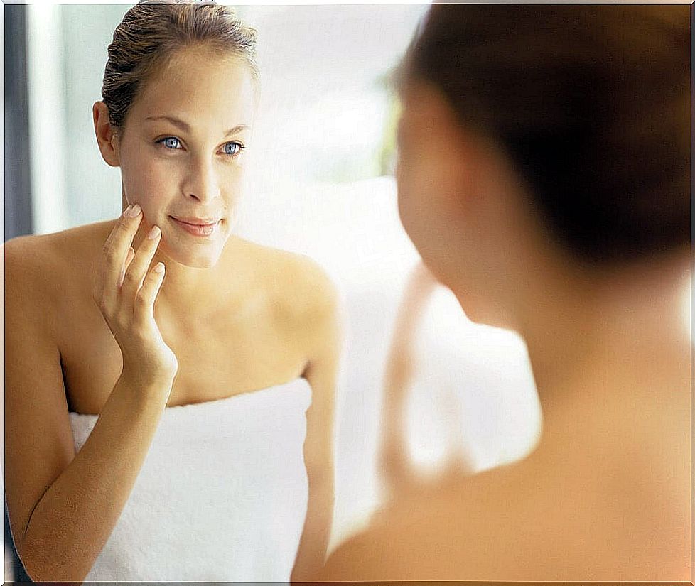 Woman looking at her skin in the mirror after applying rice water.